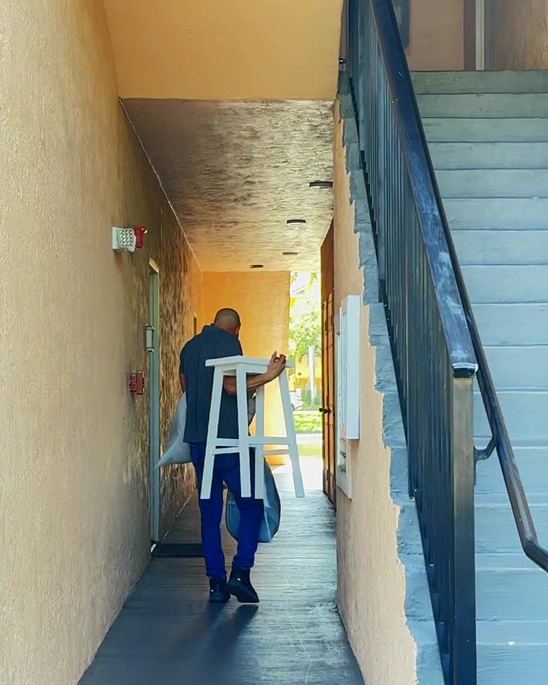Mover carrying furniture down an apartment breezeway